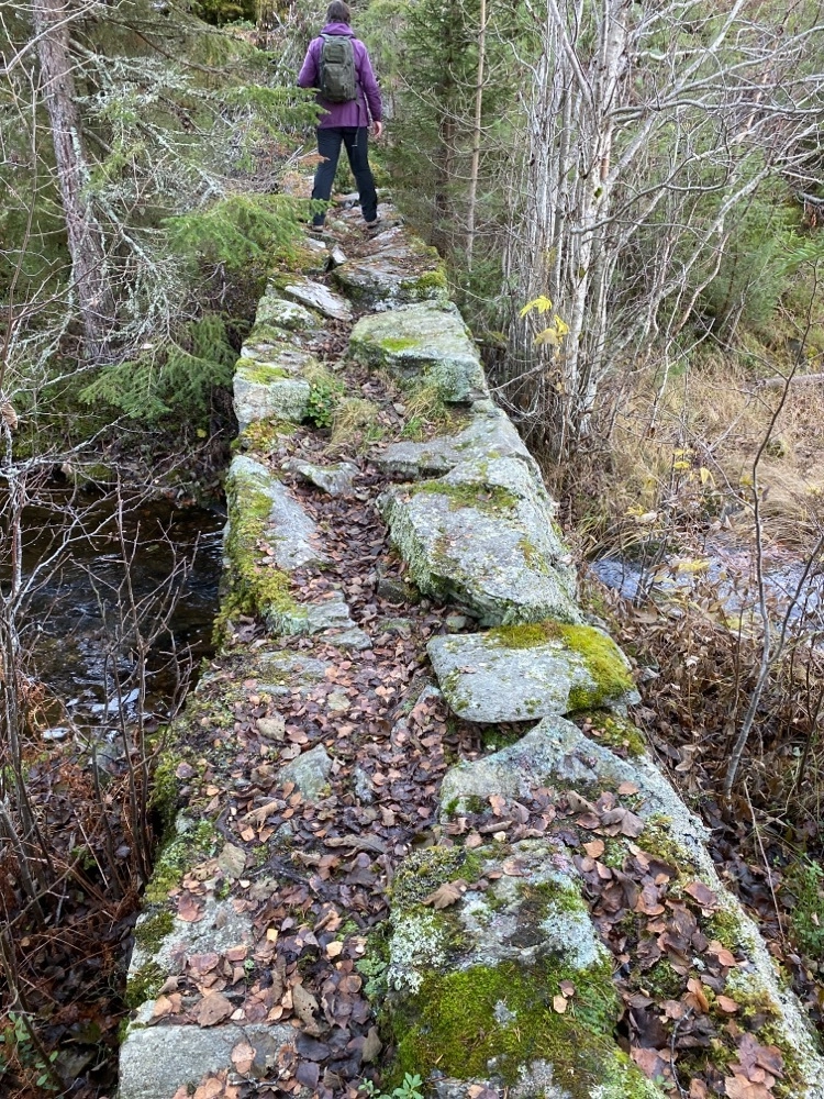Misa80 walks across an old stone bridge, showing the variety of trails encountered while geocaching.