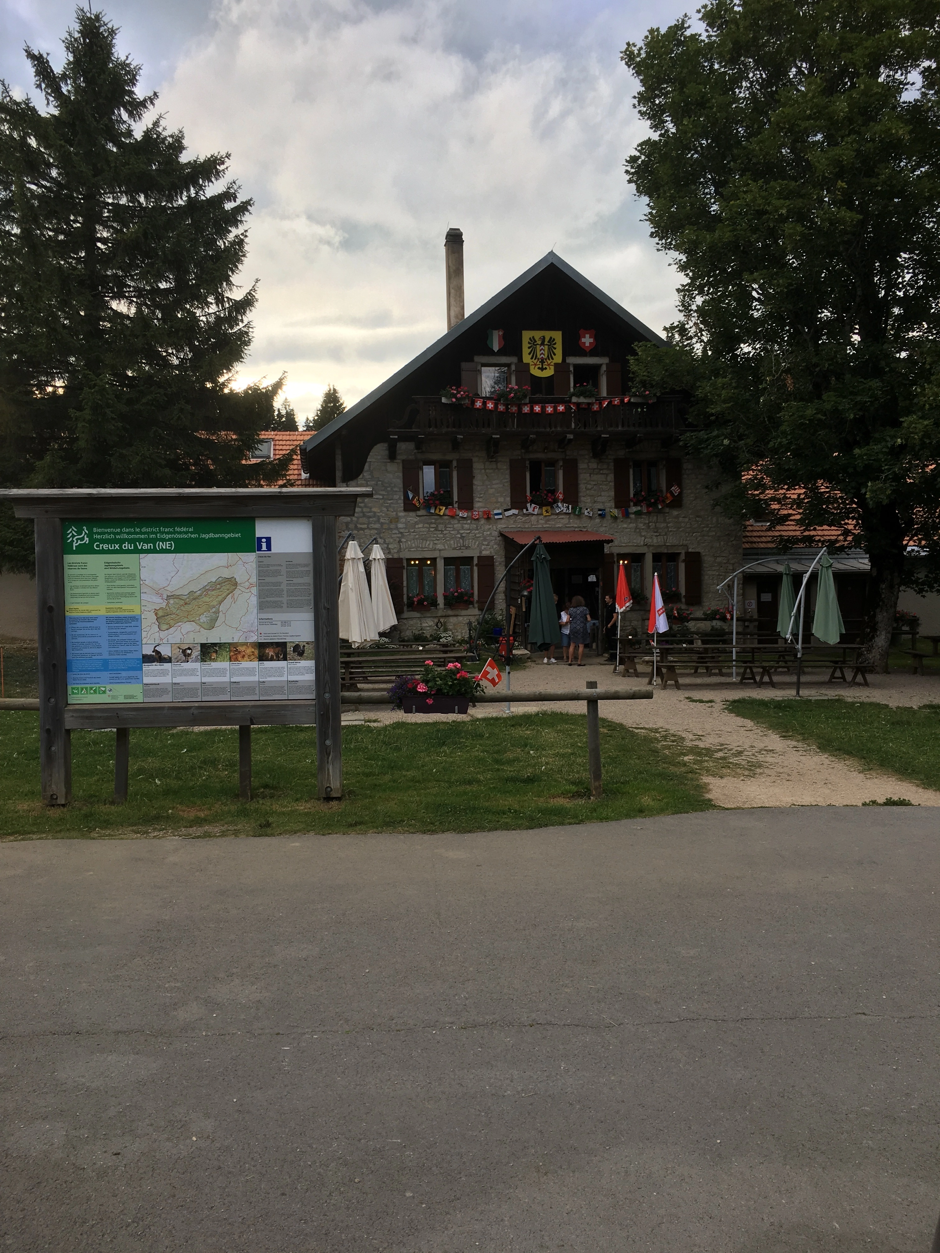 Outdoor seating with guests at the restaurant near Creux du Van, surrounded by mountain scenery