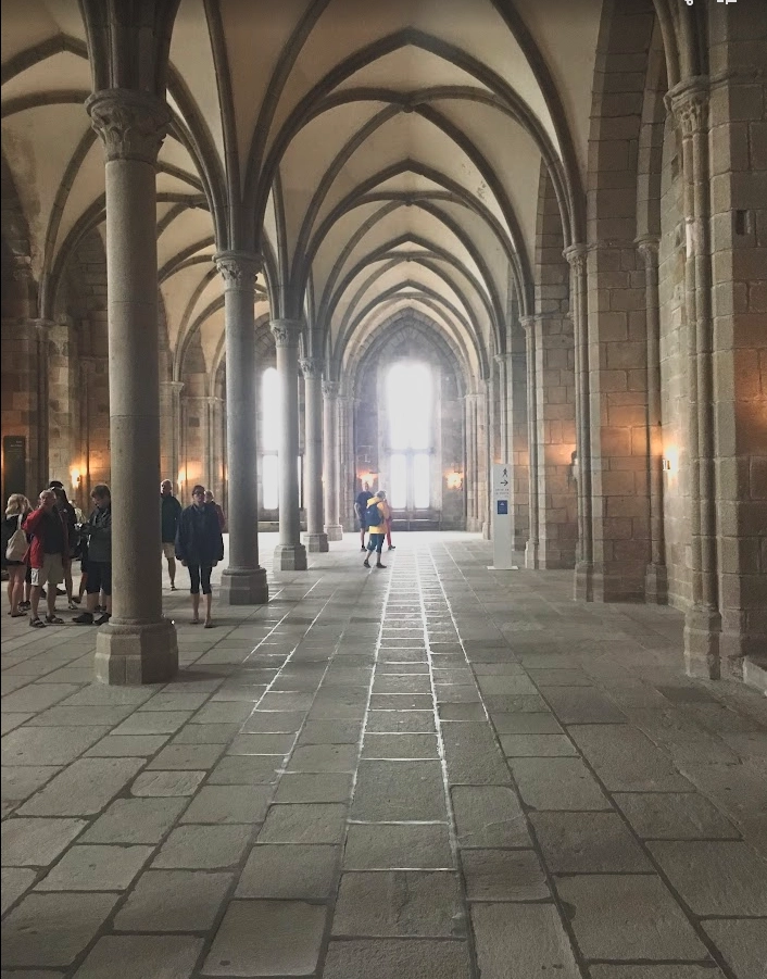 Interior view of the Mont-Saint-Michel abbey, showing its massive stone walls, high vaulted ceilings, and medieval architecture.