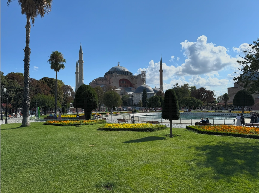 Hagia Sophia illuminated by sunlight with a green garden in the foreground