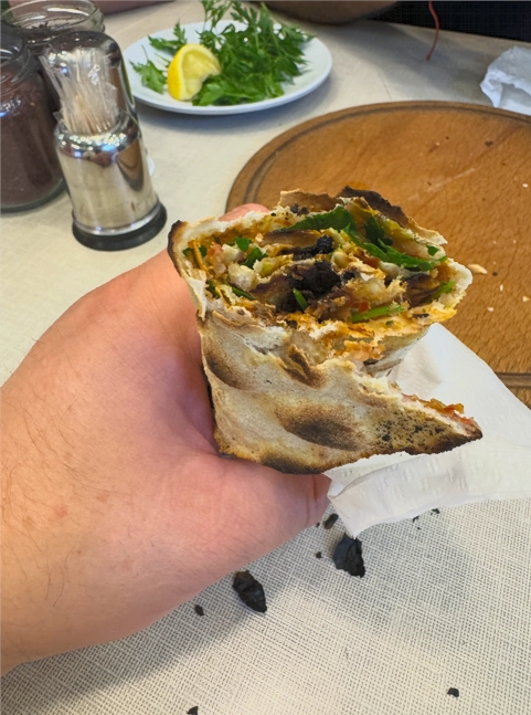 Lahmacun folded in half, filled with parsley and lemon juice